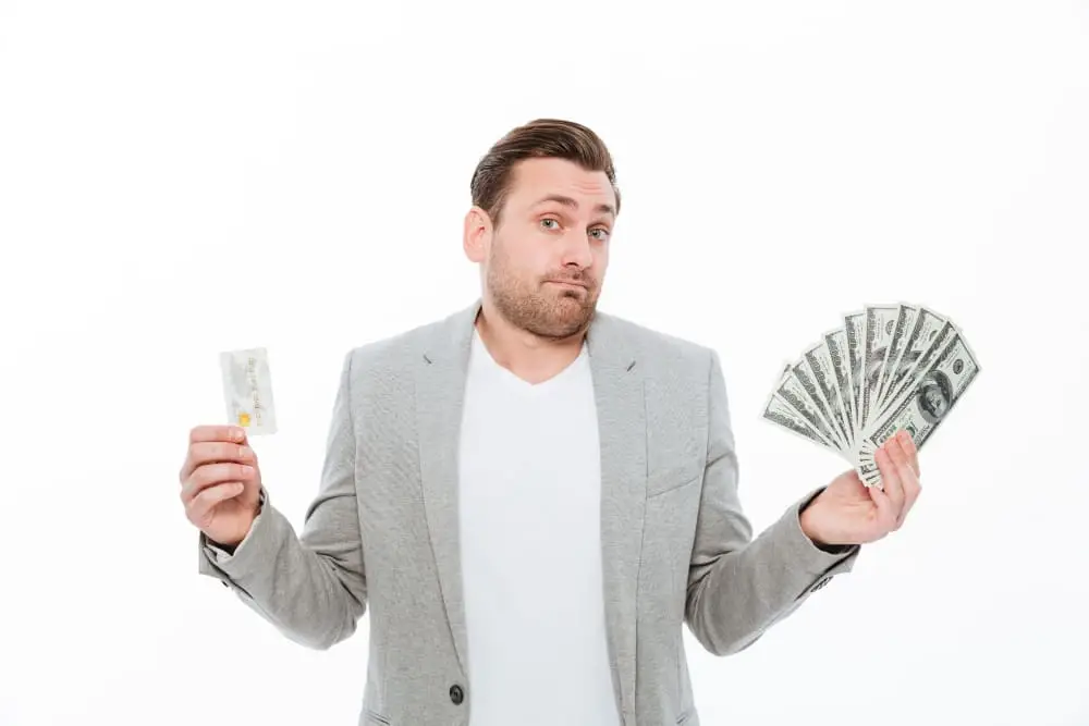 Man unsure whether to choose cash or a credit card — representing financial confusion influenced by conflicting online money advice.