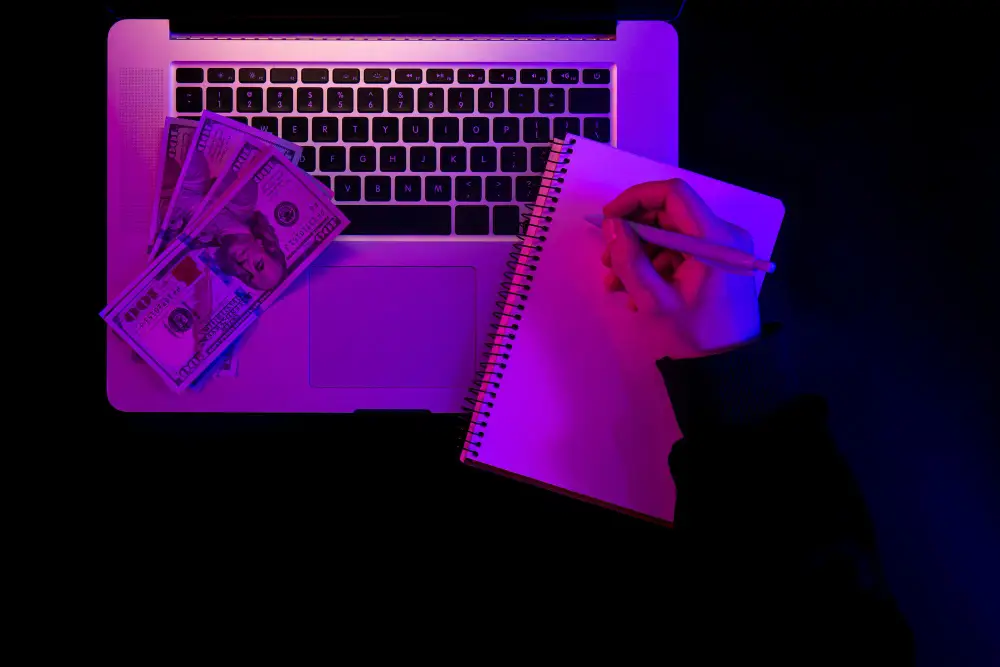 Freelancer working late at night with a laptop, US dollars, and a notebook—symbolizing modern freelance income strategies